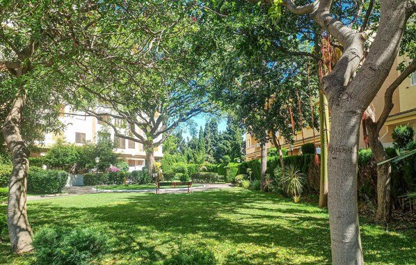 Un patio con césped, árboles y un edificio con balcones.