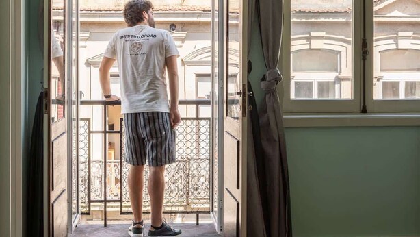 Une chambre d’hôtel avec balcon, un lit équipé d’une serviette propre, et une vue sur les bâtiments environnants.