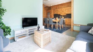 Un salon moderne avec un téléviseur à écran plat, une table basse en bois et un canapé gris.