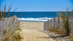 A sandy beach path leading to the ocean, bordered by wooden fences and vegetation. - Coastal Inspired Three Bedroom Oceanfront Condo (Ocean City)