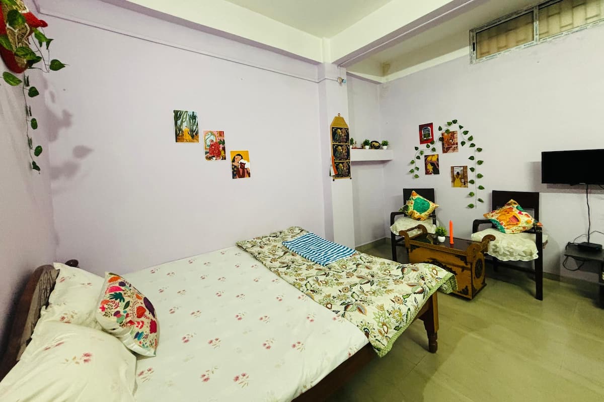 A bedroom with two beds, a TV, a wooden cabinet, and wall decorations.