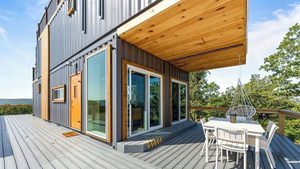 Ein modernes Haus mit Terrasse, großen Fenstern und einem Essbereich.