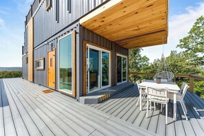 A modern house with a deck, large windows, and a dining area. - Container Home (Omaha)