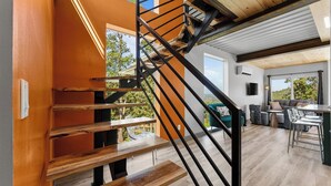 Ein modernes Interieur mit einer Holztreppe, einem Essbereich und Blick ins Freie.
