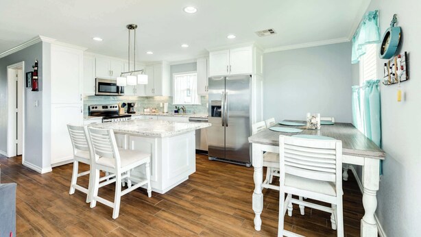 A modern kitchen with white cabinetry, stainless steel appliances, and a central island with seating.