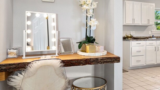 Un meuble-lavabo pour la salle de bain, avec un miroir, des luminaires et une chaise.
