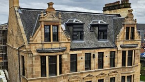 Ein historisches Gebäude mit einer steinernen Fassade, zahlreichen Fenstern und einem steil aufragenden Dach.
