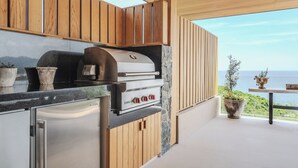 Et moderne køkken med integreret grill, stenelementer og havudsigt.