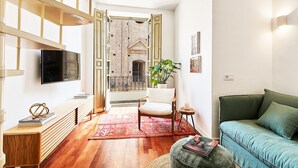 A modern living room with a wooden bench, a green sofa, a white chair, and a TV mounted on the wall. - Solaga - Dolores (Málaga)