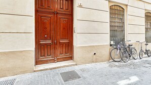A large wooden double door with a small window above it, a bicycle parked outside, and a number '2' on the wall. - Solaga - Dolores (Málaga)