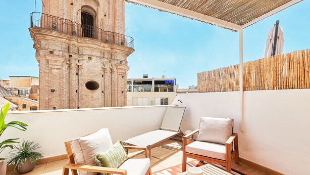 A rooftop terrace with a brick tower, wooden furniture, and potted plants. - Solaga - Dolores (Málaga)