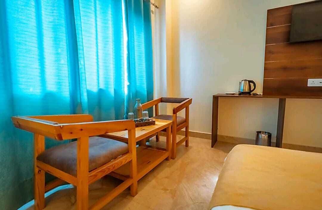 A hotel room with a bed, a wooden desk, a chair, and a TV on the wall.