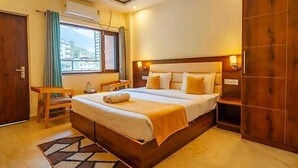 Un dormitorio con una cama grande, un armario de madera, una mesita de noche con lámpara y una ventana con cortinas.
