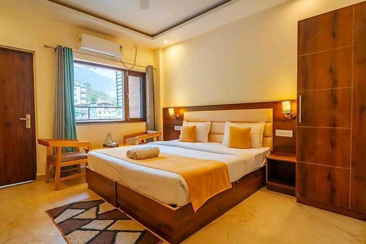 A bedroom with a large bed, a wooden wardrobe, a bedside table with a lamp, and a window with curtains.