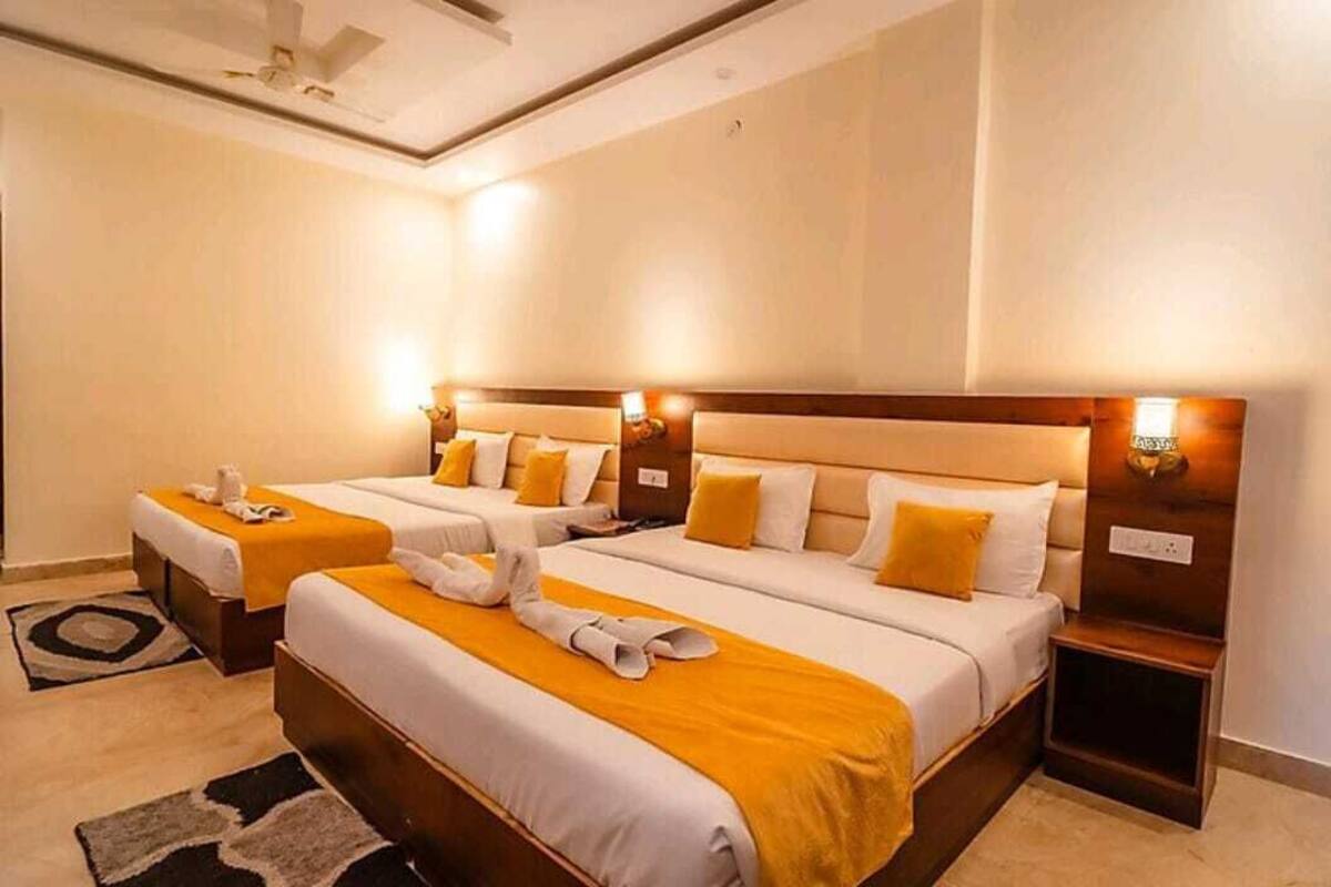 A hotel room with two beds, each with a headboard, bedside tables, and lamps.