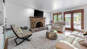 A living room with a stone fireplace, a sofa, a recliner, and a coffee table. - Spacious 3BR Redmond Home with Fireplace & BBQ (Redmond)