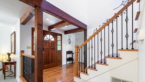 A wooden staircase with black balusters, a wooden door with glass panels, and a white wall with a vent. - Spacious 3BR Redmond Home with Fireplace & BBQ (Redmond)