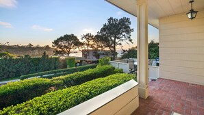 A covered patio area with a view of a landscaped garden and distant trees. - Oceanview Charmer, One Block to Beach (San Diego)