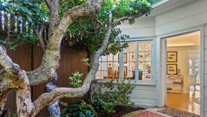 A well-maintained garden with a large tree, a brick pathway, and a wooden fence. - Oceanview Charmer, One Block to Beach (San Diego)