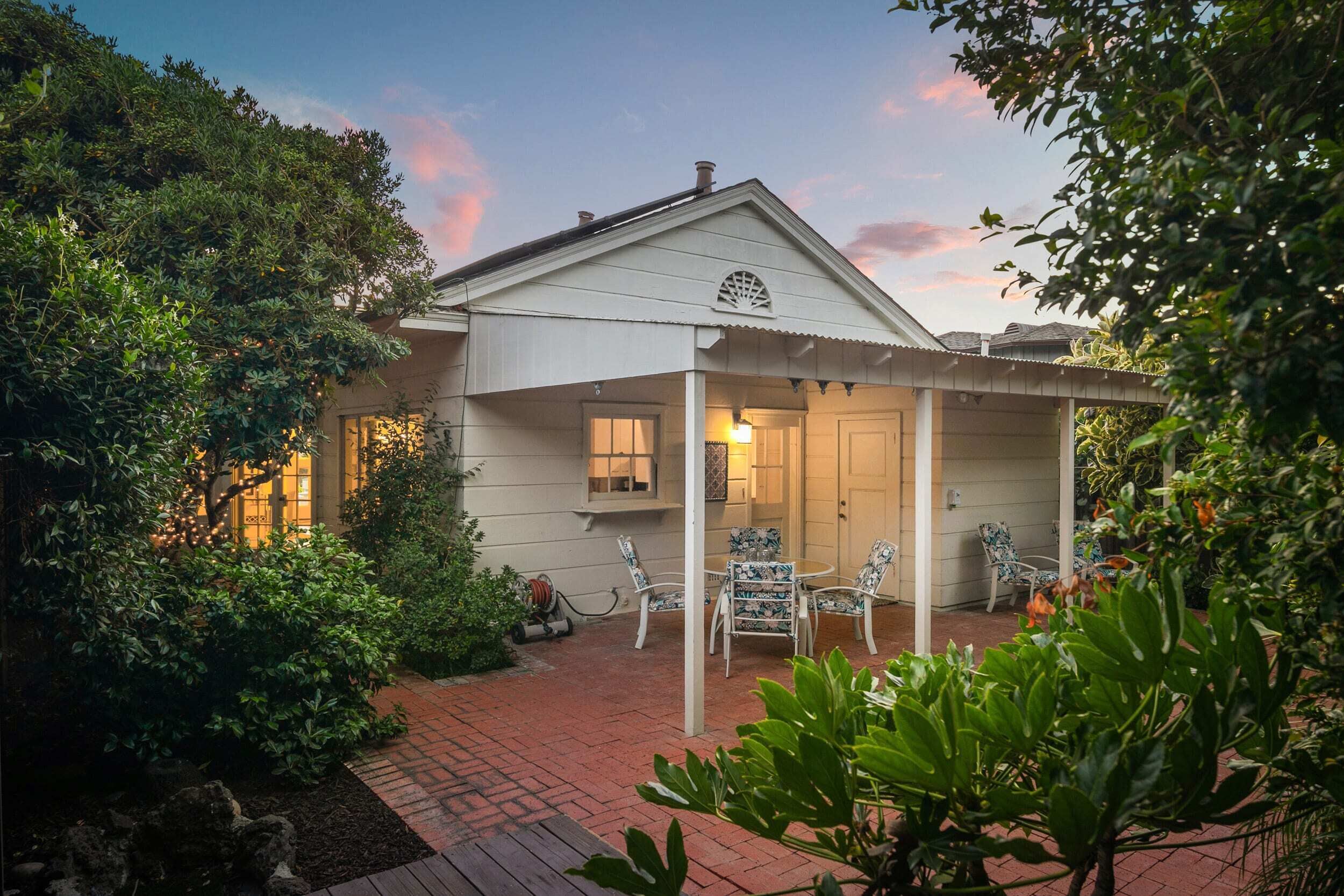 A house with a covered porch, a brick pathway, and outdoor furniture.