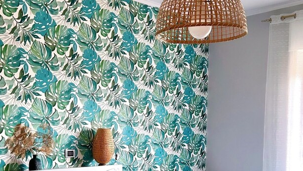 A hotel room with a large bed, a smaller bed, a woven light fixture, and a tropical leaf-patterned wall. - Delightful and spacious apartment with a view of Vesuvius - Salotto Napoletano 381 (Napoli)