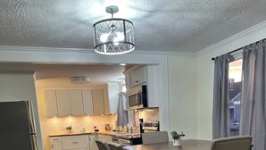 A modern kitchen with white cabinets, a dining table with chairs, and a wooden floor.