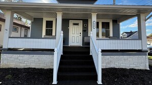 A two-story house with a front porch, a front door, and a staircase leading to the second floor.