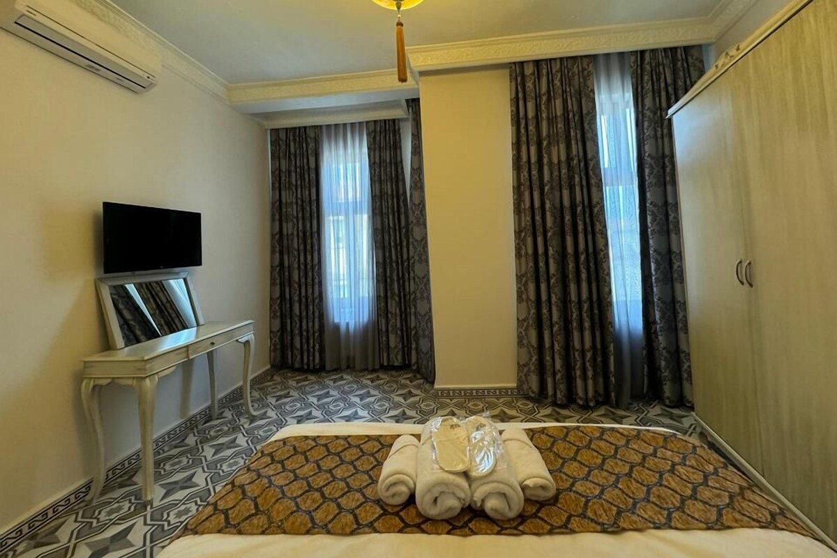 A hotel room with a bed, a flat-screen TV, a small table, and a wardrobe.