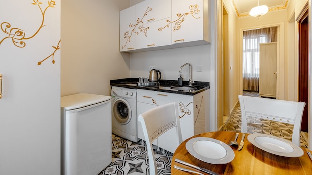 A compact kitchen with a washing machine, a sink, and a dining area with a table set for two. - Felicity Palace Sirkeci (Istanbul)
