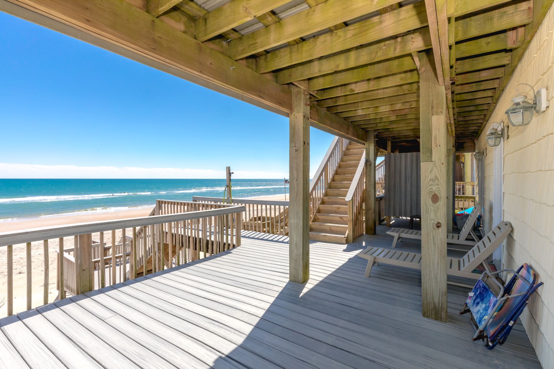A wooden deck with a view of the beach and ocean.
