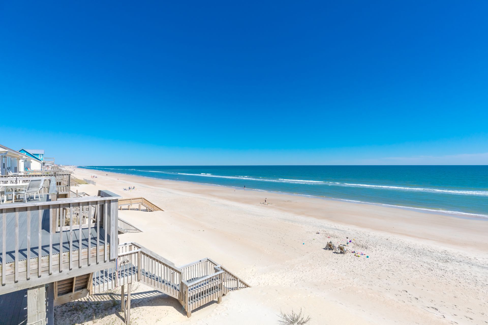 Una playa con una estructura de madera, que incluye una escalera y una terraza, con vista al océano.
