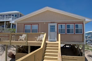 A beachfront house with a wooden deck, a front porch, and a staircase leading to the entrance. - Carolina Charm - Classic 3BR Oceanfront Cottage, Dog Friendly! (Surf City)