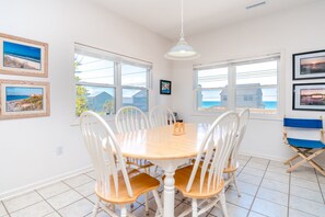 A dining area with a round table, white chairs, and a hanging light fixture. - Almost Beachfront - Cozy 2nd Row Home with 4 Bedrooms (Surf City)
