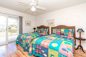 Un dormitorio con dos camas, ventilador de techo y vistas al exterior.