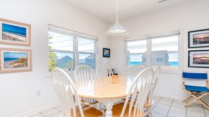 A dining area with a round table, white chairs, and a blue folding chair. - Almost Beachfront - Cozy 2nd Row Home with 4 Bedrooms (Surf City)