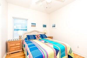 A bedroom with a bed, a nightstand, a dresser, and a window with blinds. - Almost Beachfront - Cozy 2nd Row Home with 4 Bedrooms (Surf City)