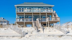 A multi-story beachfront house with a wooden deck and stairs leading to the entrance. - Bilou's - Oceanfront! Dog Friendly! (North Topsail Beach)