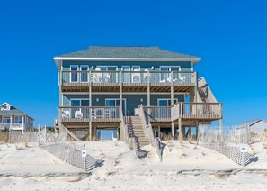 A multi-story beachfront house with a wooden deck and stairs leading to the entrance. - Bilou's - Oceanfront! Dog Friendly! (North Topsail Beach)