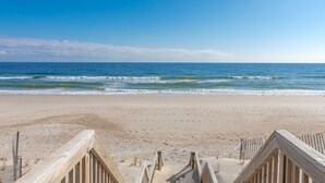 A beach with wooden boardwalks leading to the water, clear skies, and calm waves.
