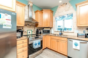 A kitchen with wooden cabinets, a stainless steel refrigerator, a stove, and a microwave.