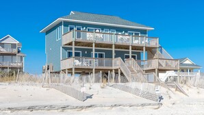 A multi-story beachfront building with balconies, a wooden deck, and a sandy beach in the foreground. - Bilou's - Oceanfront! Dog Friendly! (North Topsail Beach)