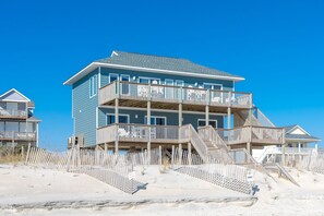A multi-story beachfront building with balconies, a wooden deck, and a sandy beach in the foreground. - Bilou's - Oceanfront! Dog Friendly! (North Topsail Beach)