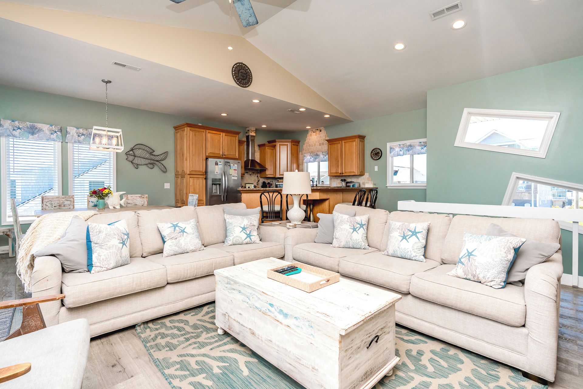 A living room with a sectional sofa, a coffee table, and a kitchen in the background.