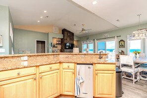 A kitchen with granite countertops, wooden cabinets, a built-in refrigerator, and a ceiling fan.
