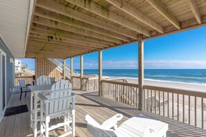 A wooden deck with outdoor seating and a view of the ocean. - Bilou's - Oceanfront! Dog Friendly! (North Topsail Beach)