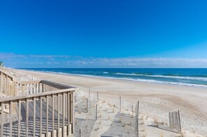 A wooden boardwalk leading to a beach with a clear view of the ocean.