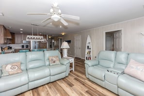 A modern living room with two light blue leather sofas, a white ceiling fan, and a wooden floor.