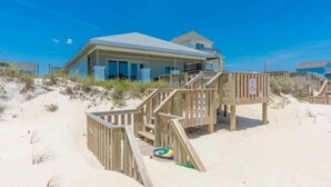 Une propriété située en bord de mer, dotée d’une terrasse en bois, d’un ballon de plage et surplombant un ciel bleu azur.