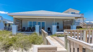 Une maison située en bord de mer, dotée d’un porche couvert, d’un espace salon extérieur et d’une terrasse en bois.