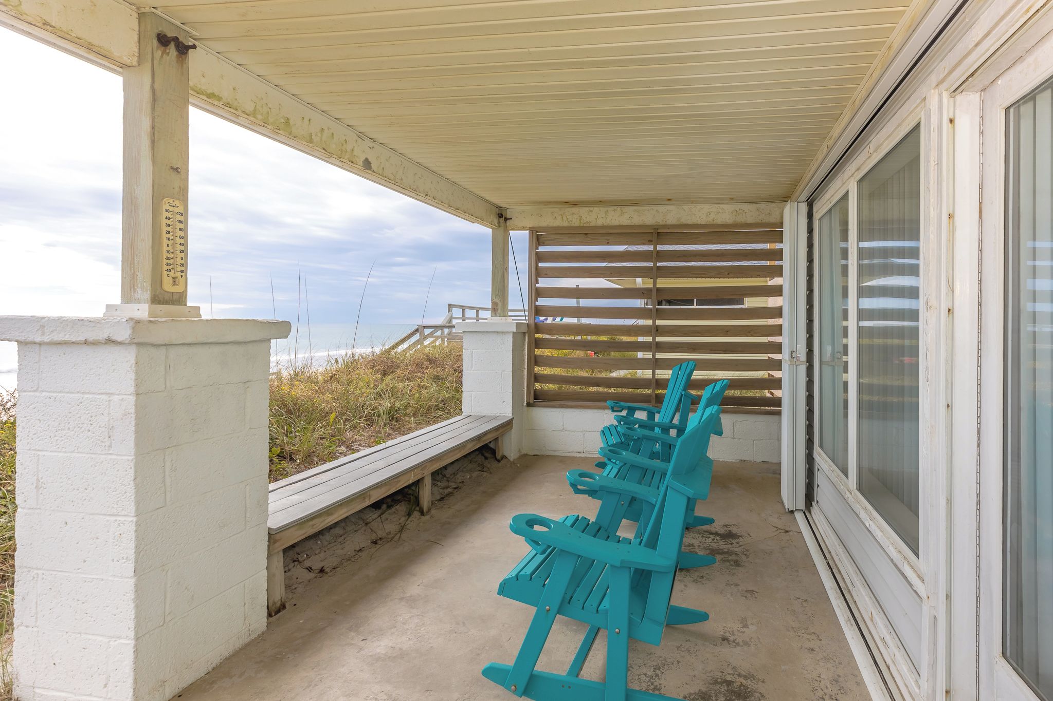 Un espace extérieur abrité, doté de bancs et offrant une vue sur la plage.